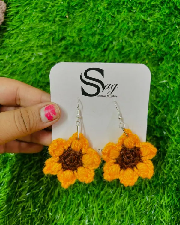 My handmade crochet sunflower earrings, held up to show their detail. They are lightweight and attached to quality earring hooks.
