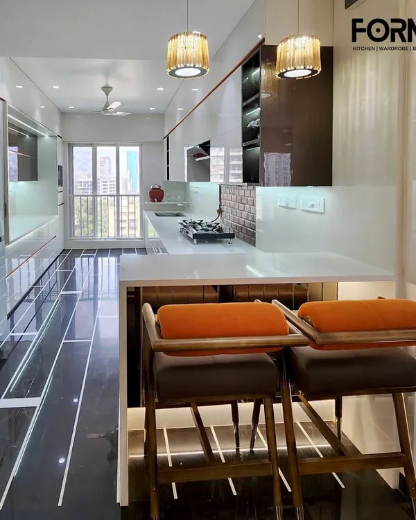 A bright, open-plan kitchen featuring a sleek white breakfast bar with stylish seating. This design integrates the kitchen with the living area, using high-gloss white cabinetry, contrasting black marble flooring, and elegant pendant lighting to create a luxurious and social space.