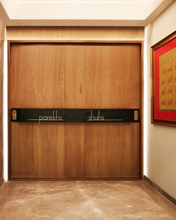 We transformed a single large apartment into two distinct homes for related families, starting with this shared entrance that uses a sliding wooden door to cleverly designate the two residences.