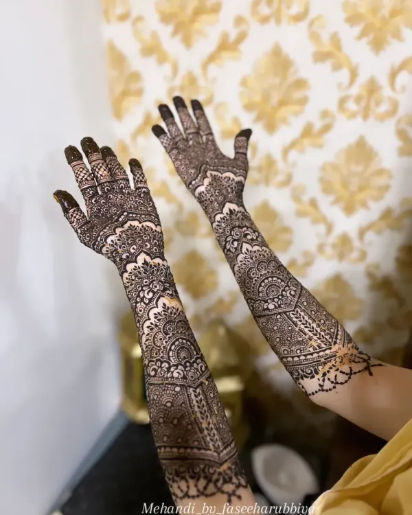 A beautiful example of full-coverage engagement henna, featuring geometric patterns and traditional motifs extending up the forearm.