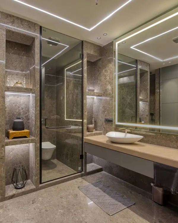 This modern bathroom is a showcase of integrated lighting and luxurious materials. We used marble-clad walls with built-in, illuminated niches for storage and display, creating a warm and functional space.