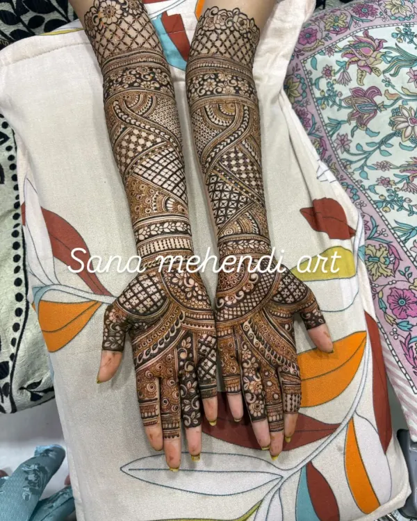 A classic full bridal mehendi design, extending from the fingertips to the elbows. This style is rich with intricate details, including fine lines, jaali work, and bold patterns for a stunning effect.