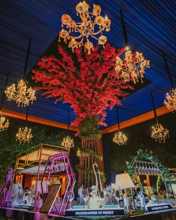 The centerpiece of a spectacular cocktail night. I designed this custom bar with a magnificent red floral tree and cascading chandeliers to create a breathtaking focal point. It’s a perfect blend of art and hospitality for a high-end sangeet event.