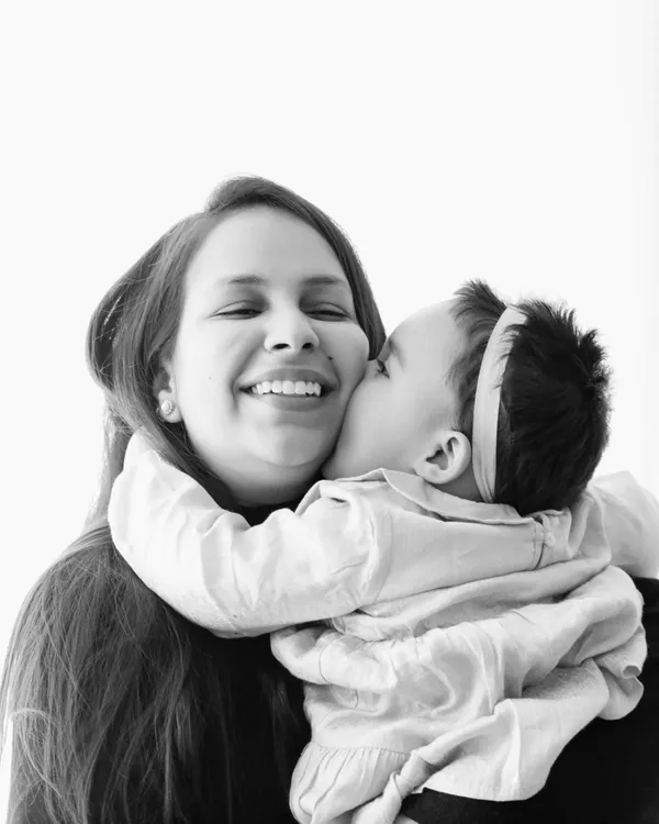 An emotional black and white portrait of a baby kissing her mother's cheek. This style beautifully captures pure affection and joy.
