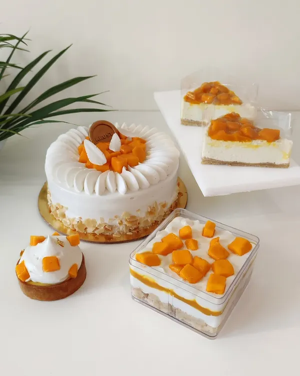A beautiful spread showcasing my seasonal mango specials. This collection includes a full Mango King Cake, individual mango cheesecakes, a mango tart, and a layered mango trifle dessert box.