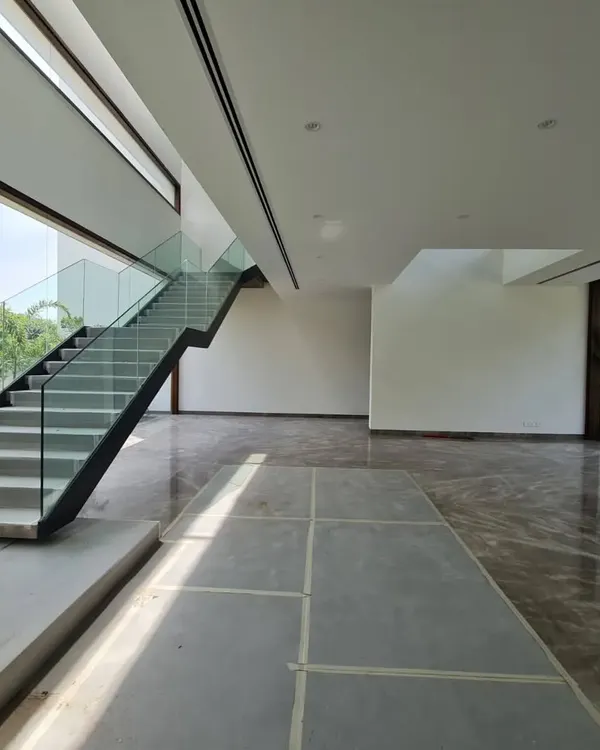 An in-progress shot of a farmhouse project, revealing the raw structure of the space. This view shows the double-height window and staircase before the finishes, furniture, and lighting are installed.