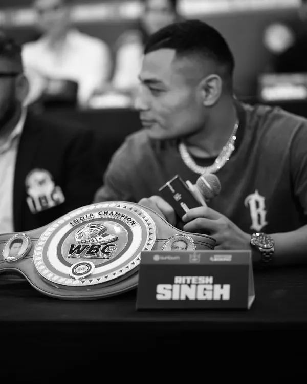 From dreams to the belt. A black and white shot of our fighter Ritesh Singh with his hard-earned WBC India Champion belt at a press conference.