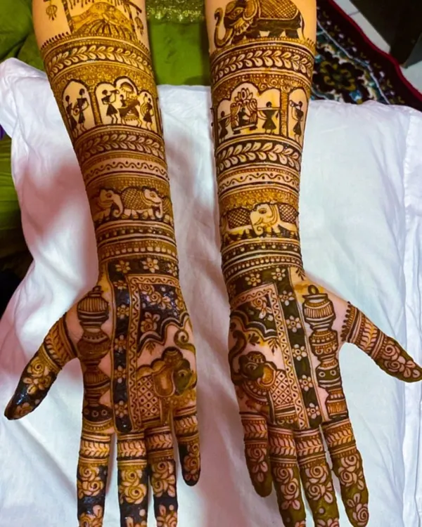 A bridal theme design telling a story on the arms. This mehendi features figures from a wedding procession, including elephants and doli scenes, making it a truly unique piece of art.