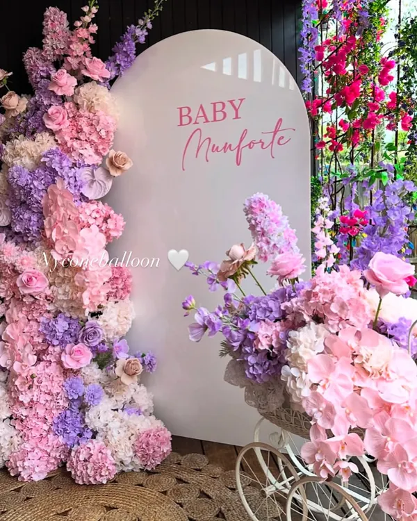 I love creating these lush, flower-filled backdrops for events like baby showers. This setup for 'BABY Munforte' uses a beautiful mix of pink and purple florals to create a stunning photo corner.