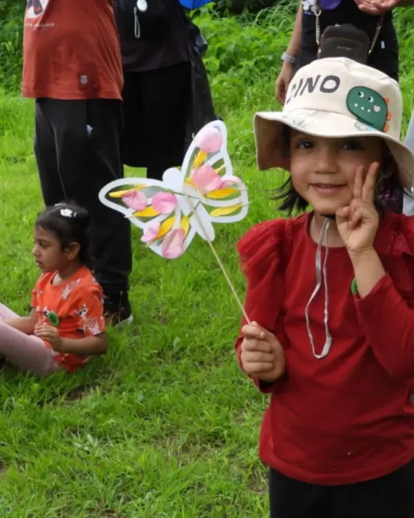 A proud five-year-old shows off her handmade butterfly craft during her nature-themed birthday party on the outskirts of Mumbai. We love seeing families choose muddy, meaningful experiences to celebrate milestones.