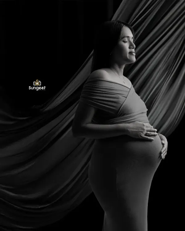 A dramatic and artistic black and white portrait. We used flowing fabric and directional light to sculpt the scene and create a powerful, emotional image of the mother-to-be.