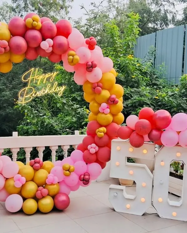 Fifty and fabulous. This vibrant outdoor setup for a 50th birthday proves that celebrations can be full of color and life. The circular balloon arch in shades of pink, red, and yellow, paired with marquee numbers, created the perfect festive backdrop.