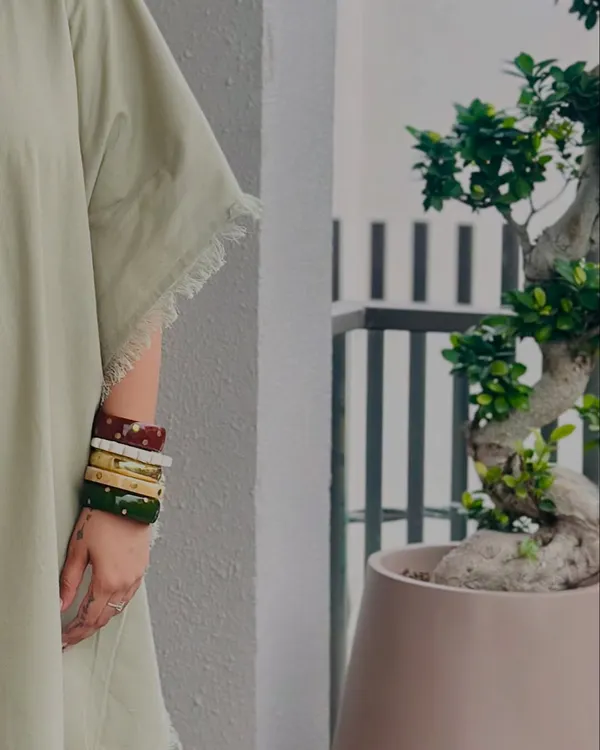 Here is a close-up of my handmade wooden bangles. I love stacking different colors and finishes to create a personalized look. They add an earthy, artisanal touch to any outfit, like this simple green kaftan.