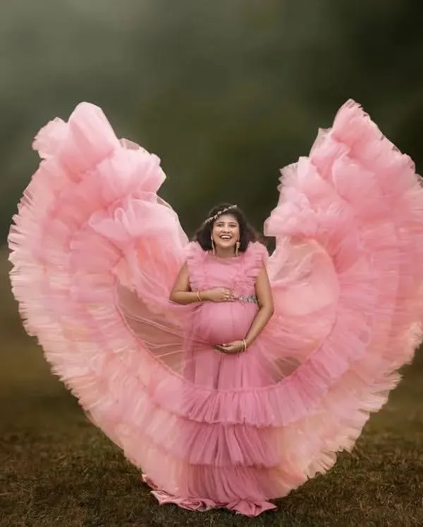 The butterfly effect in full bloom. This stunning pink ruffled gown creates a heart shape, beautifully framing the mom-to-be. It's a whimsical and joyful choice for an outdoor maternity session.