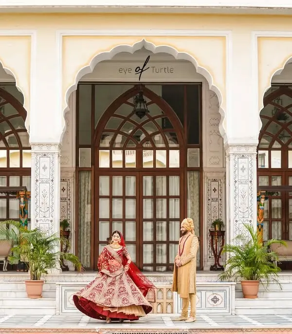 Together, they built a life they loved. This wide shot captures the couple in front of a majestic palace, the bride's twirl adding a touch of joyful movement to a grand and royal portrait.