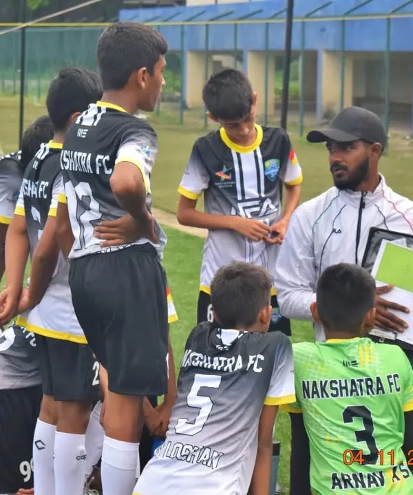 A coach explaining tactics to the U-13 team using a strategy board during a break in the Karnataka Youth Premier League. Game intelligence is as important as physical skill.