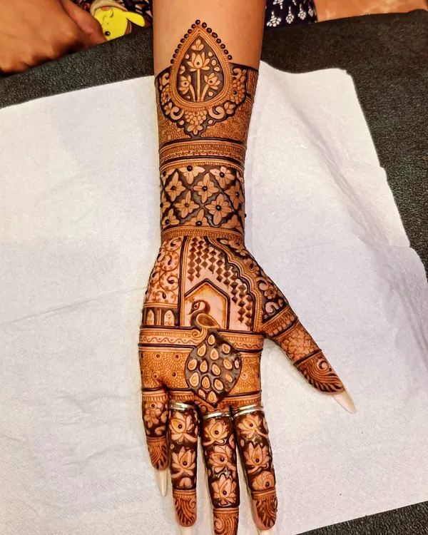This is a classic Teej special design, featuring a single hand with intricate Rajasthani patterns. The peacock and `jharokha` (window) motifs are timeless and elegant.
