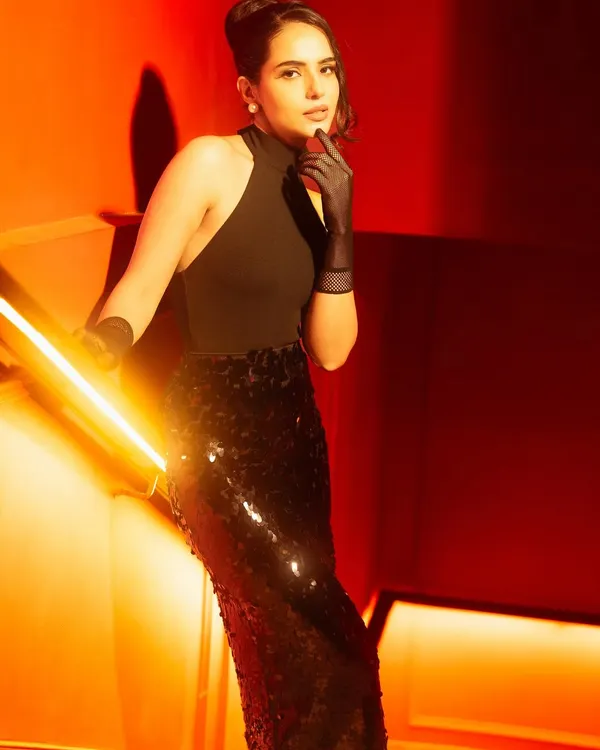 Shot in warm tungsten tones against a vivid crimson backdrop to create depth and drama. The low key light sculpts the model's contours, while the upward camera angle creates a statuesque and cinematic feel.