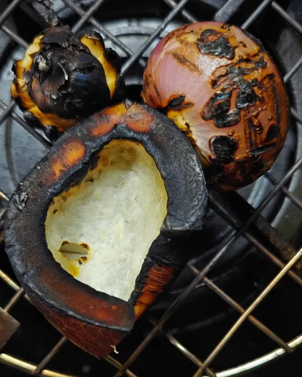 The secret to the deep, smoky flavour in dishes like Chicken Kale Sukkha is charring the ingredients. Here, I'm roasting dry coconut, onion, and garlic directly on the flame before grinding them into a masala.