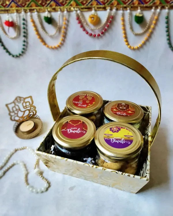 This is my classic four-jar Diwali hamper, beautifully arranged in a golden basket. It includes two cake jars, pistachio nankhatai, and peri peri makhana, all with festive 'Happy Diwali' labels.