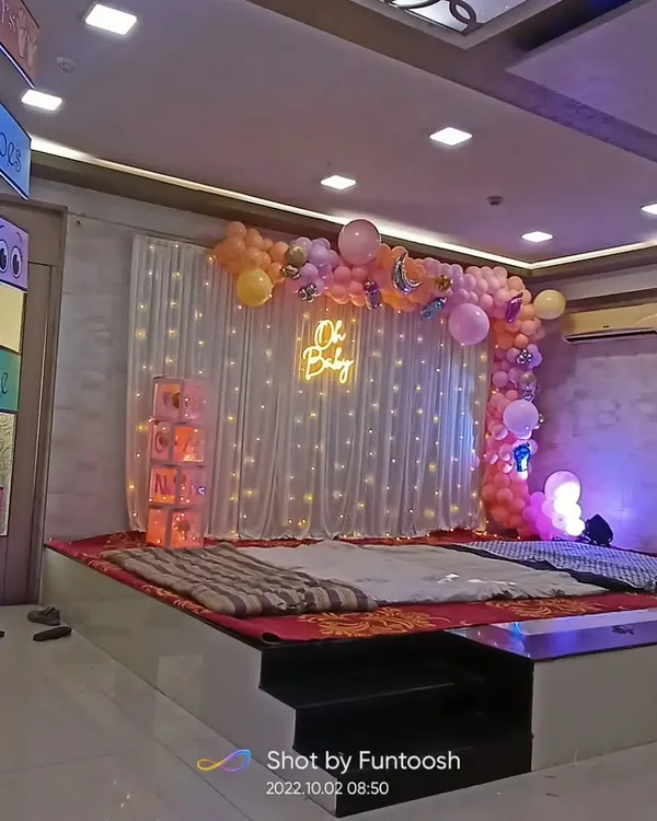 A full view of our 'Oh Baby' themed baby shower stage decoration. The setup includes a fairy light curtain, a pastel balloon arrangement, and an illuminated 'Oh Baby' neon sign.