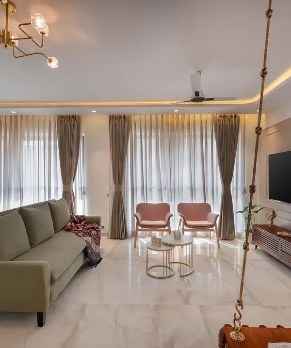 We love the cheerful vibe of this pastel-themed living room. The combination of the olive green sofa, pink armchairs, and a traditional wooden swing creates a space that is both chic and deeply personal.