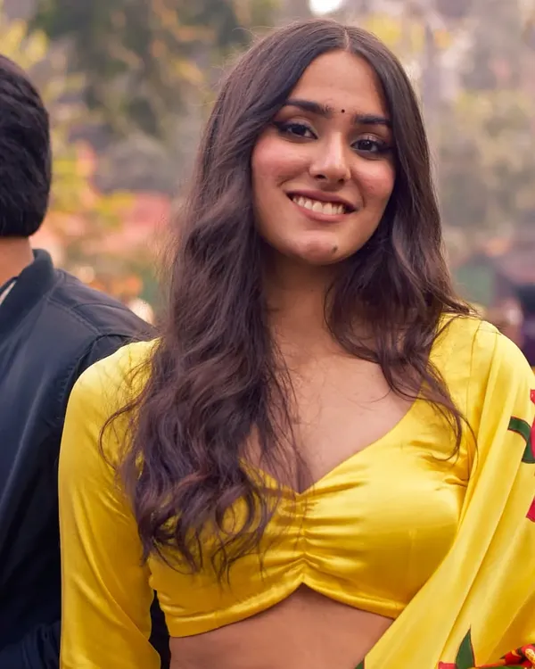 A natural and relaxed portrait of a woman in a vibrant yellow saree. The soft, diffused outdoor light and her comfortable smile make for an authentic and beautiful candid shot.