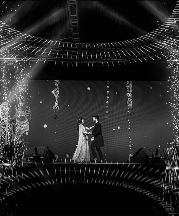 A grand stage, dramatic lighting, and a couple lost in their dance. This shot captures the epic scale and cinematic feel of a Sangeet performance, complete with pyrotechnics.