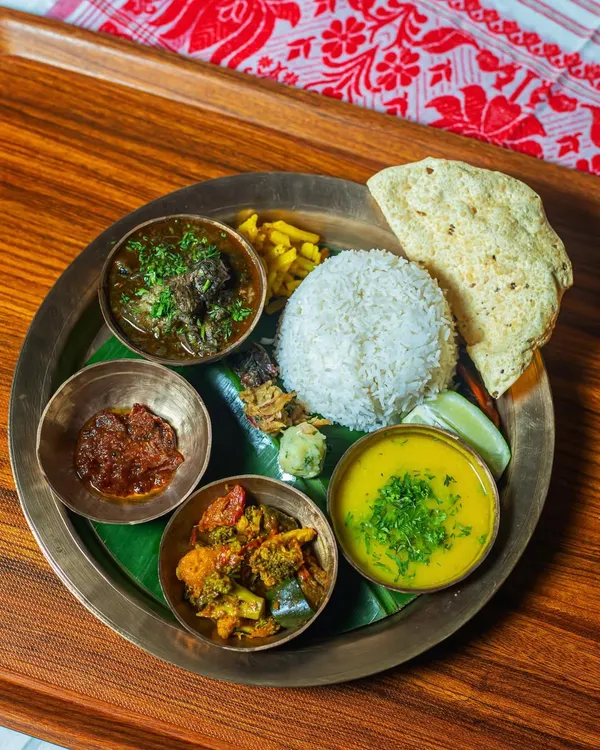 This is my Chef’s Special Assamese Till Pork Thali, a dish that truly represents the soul of Assam. The pork is slow-cooked with a rich, nutty paste of black sesame seeds, creating a deep, earthy flavor. Served on a traditional Kansa plate over a banana leaf, it comes with our house daal, a seasonal vegetable stir-fry, a fiery chutney, and steamed rice.