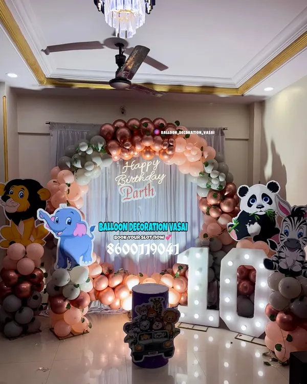 A jungle animal theme for Parth's 10th birthday. This home setup features a balloon arch in rose gold and pastel colors, with cutouts of a lion, elephant, panda, and zebra.