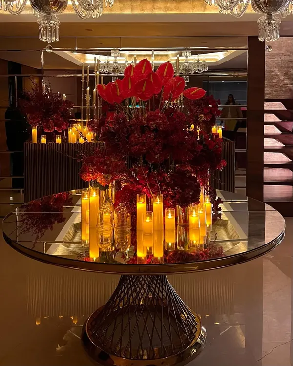 For a luxurious home birthday, we created a dramatic atmosphere using masses of crimson flowers and glowing candles on mirrored and metallic surfaces to reflect the light beautifully.