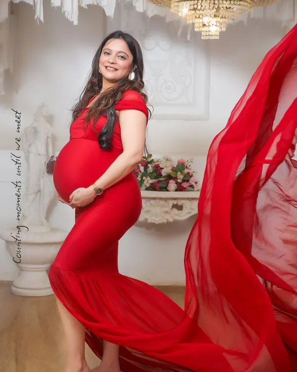A vibrant red gown brings such life and energy to a maternity portrait. The flowing fabric adds a touch of drama, perfectly highlighting the baby bump in this studio shot.