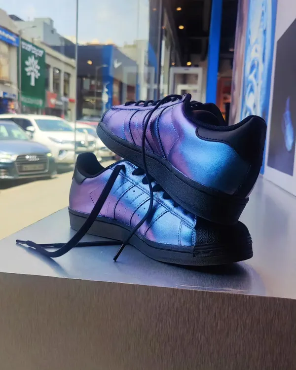 A pair of custom Adidas Superstars I painted with an iridescent, color-shifting effect. This photo was taken during a live painting event at an Adidas store, where I customized footwear for customers on the spot.