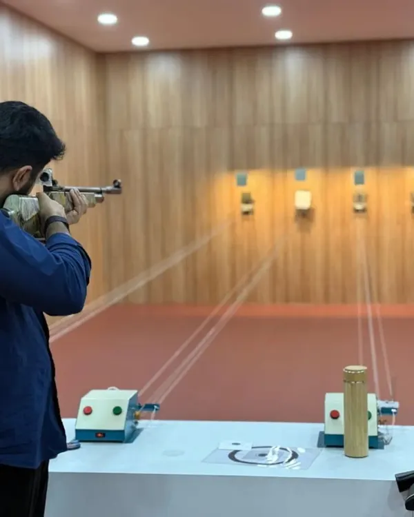 A shooter takes a focused stance, aiming down the sights of the air rifle. This moment of intense concentration is what the sport is all about.