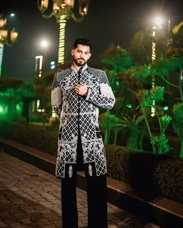 A full-length view of our black Indo-Western jacket with intricate ivory embroidery. Paired with black trousers, it creates a commanding presence, perfect for a wedding reception or formal event.