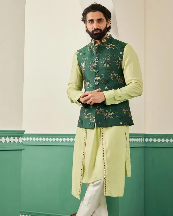 The emerald green bundi set, a perfect choice for mehendi or sangeet functions. The rich green of the embroidered jacket contrasts beautifully with the light green draped kurta.