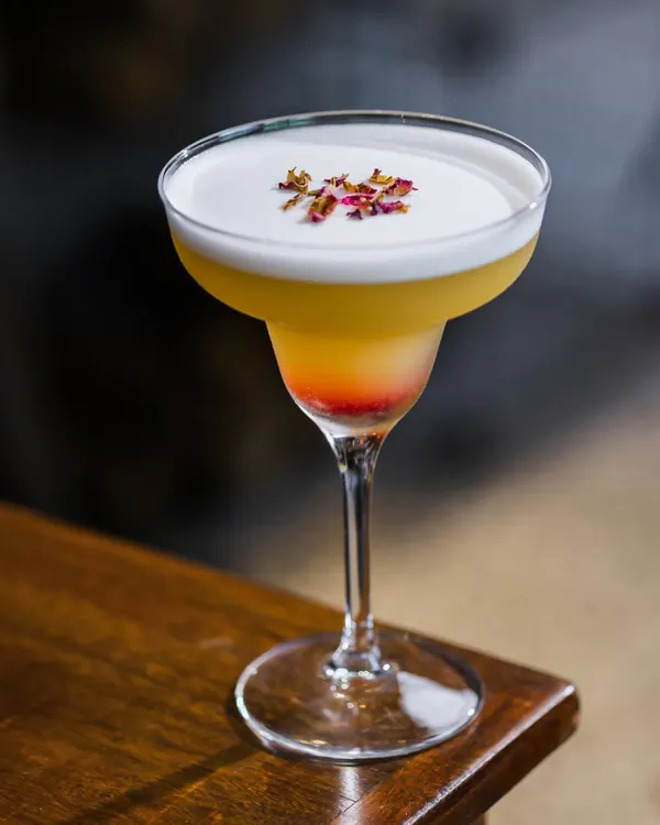 This is my Almafi mocktail, a layered drink with a frothy top and a sprinkle of dried rose petals. It's a light and refreshing choice, perfect for sipping slowly on a warm day.