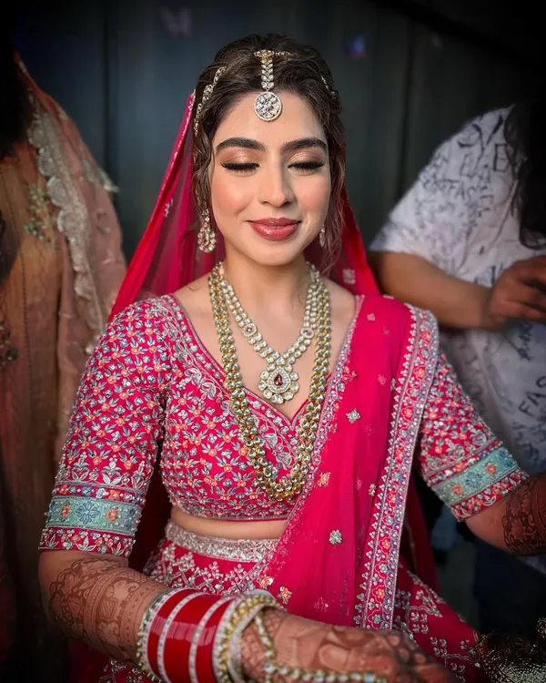 Creating timeless beauty for Jasleen's big day. This look features soft, blended eyeshadow and a classic pink lip to complement her intricately embroidered pink lehenga.