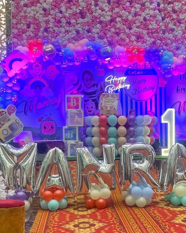 A full view of the spectacular Cocomelon first birthday party setup. The arrangement includes large foil letters for the name, a themed backdrop, balloon arches, and character cutouts, creating an immersive experience for the little one and the guests.