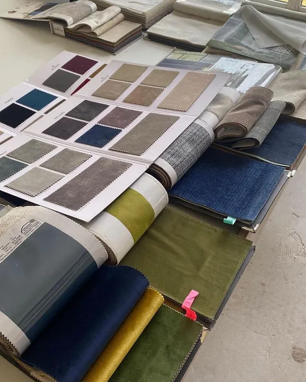 The design process starts with a sea of possibilities. Here, our table is covered with fabric swatch books as we curate the perfect color and texture palette for a new home.