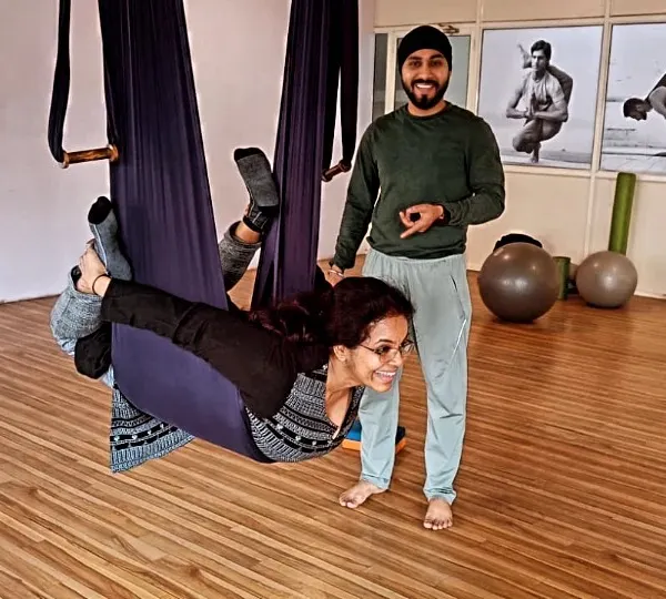 (Hero Item) As your guide, my hands-on approach is central to my teaching. Here, I am assisting a student in an aerial yoga hammock, ensuring she feels secure and can safely explore the pose. It is all about finding that balance between challenge and support.