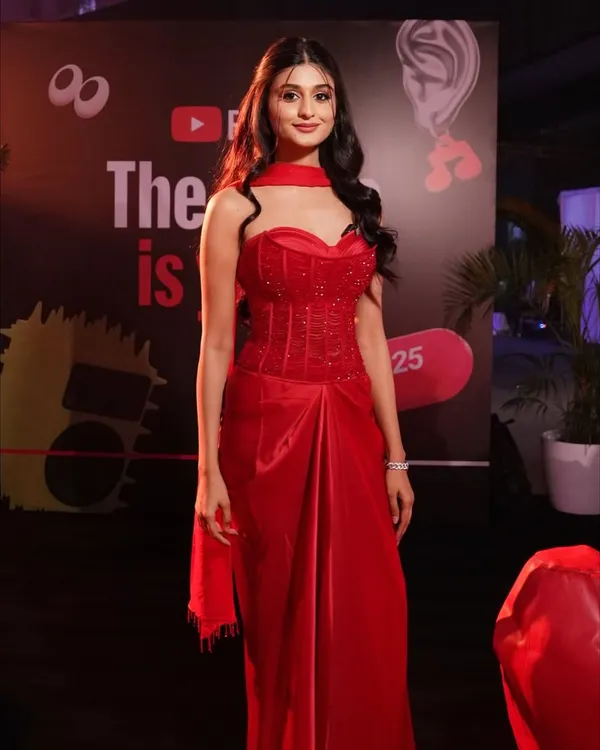 A full-length shot of Payal Gaming at the YouTube Fanfest, showcasing how the complete makeup and hair look comes together with her stunning red gown for a cohesive and show-stopping red carpet presence.