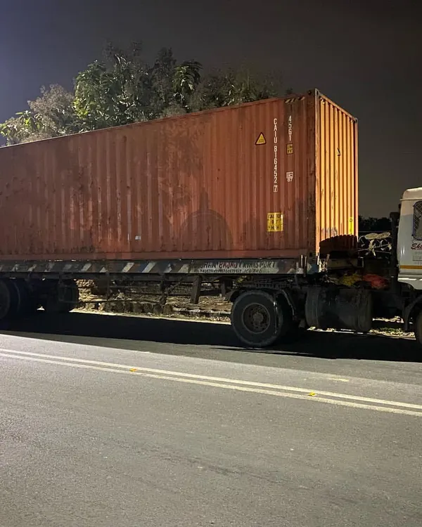 The journey begins. A 40-foot shipping container arrives on a truck at night, ready to be repurposed into a key component of a new architectural project.