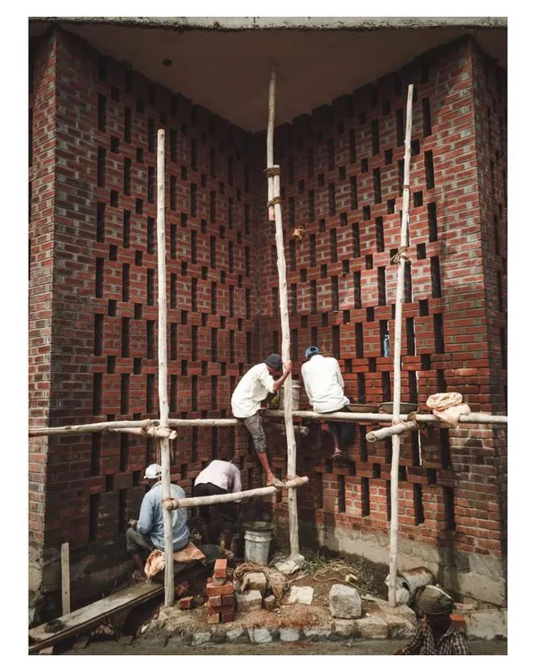 Masons at work on the intricate brick jali wall of the Dr. Vishnuvardhan Memorial. This image captures the human skill and craftsmanship involved in realizing the design.