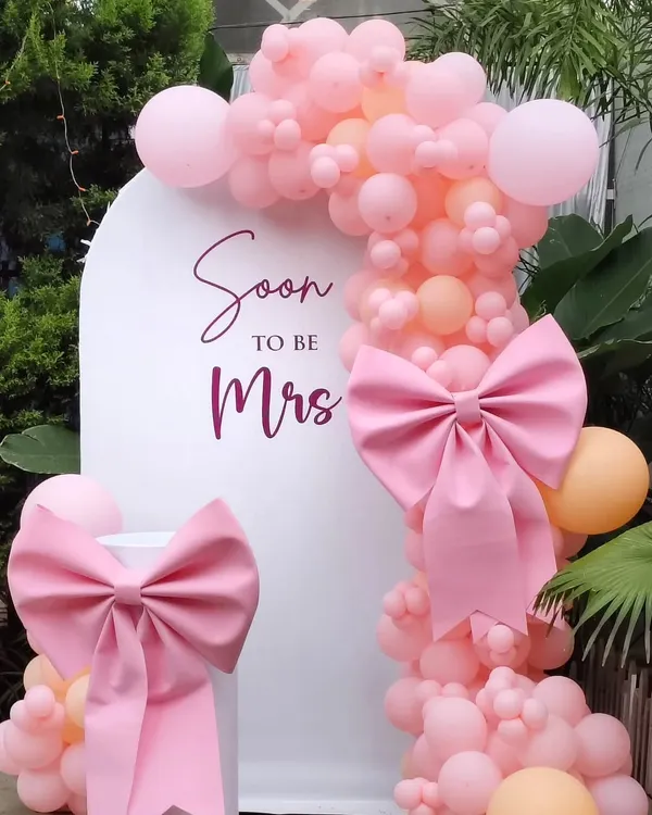 This 'Soon to be Mrs' bridal shower setup is a favorite for its feminine charm. I used a clean white arch backdrop, a lush garland of pink and peach balloons, and finished it with oversized pink bows for a touch of playful elegance.