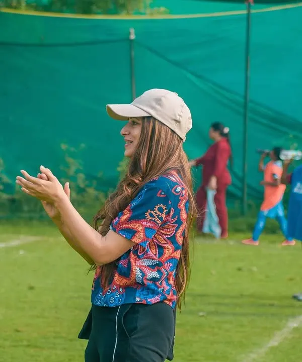 A mother cheers enthusiastically from the sidelines, her support fueling the players on the field.