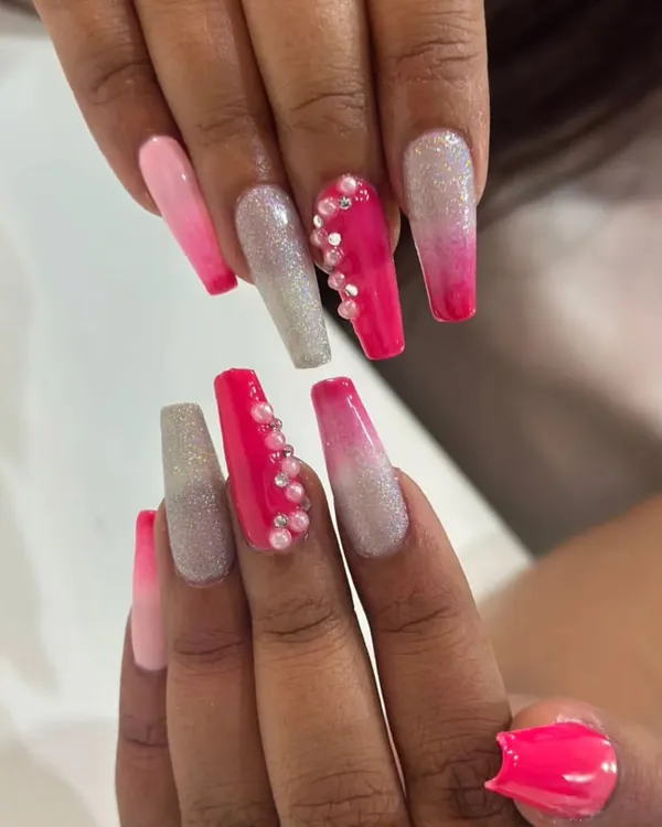 This long coffin nail set is all about vibrant color and sparkle. It features a pink ombre, silver glitter, and a hot pink accent nail with a cascade of pearl embellishments.