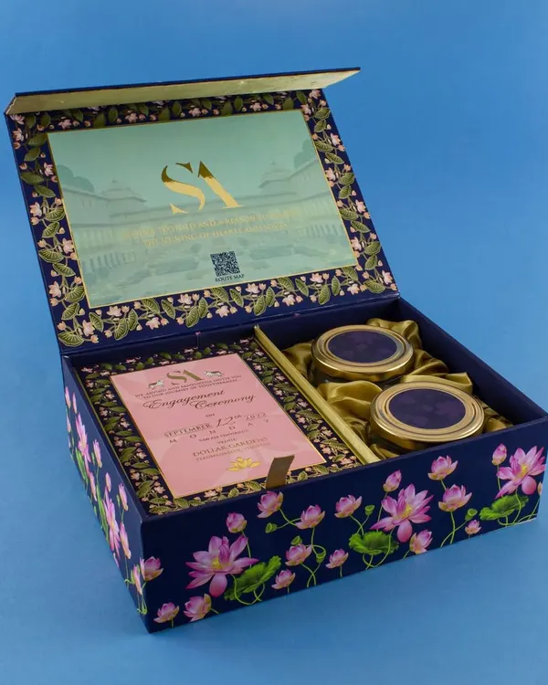 This deep blue box features a beautiful lotus pond design that continues on the inside. It includes space for the main invitation card and two matching jars for sweets, all tied together with a satin ribbon.