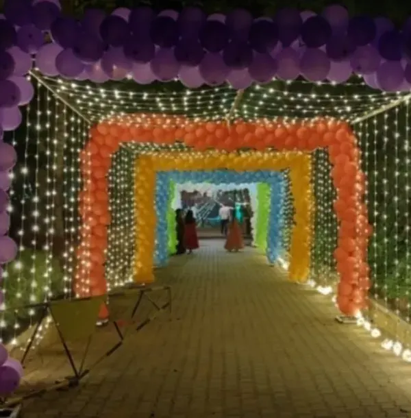 Make a grand entrance with this spectacular rainbow balloon tunnel. Lined with fairy lights, this immersive installation creates a magical pathway for guests, perfect for large outdoor evening events and birthday parties.