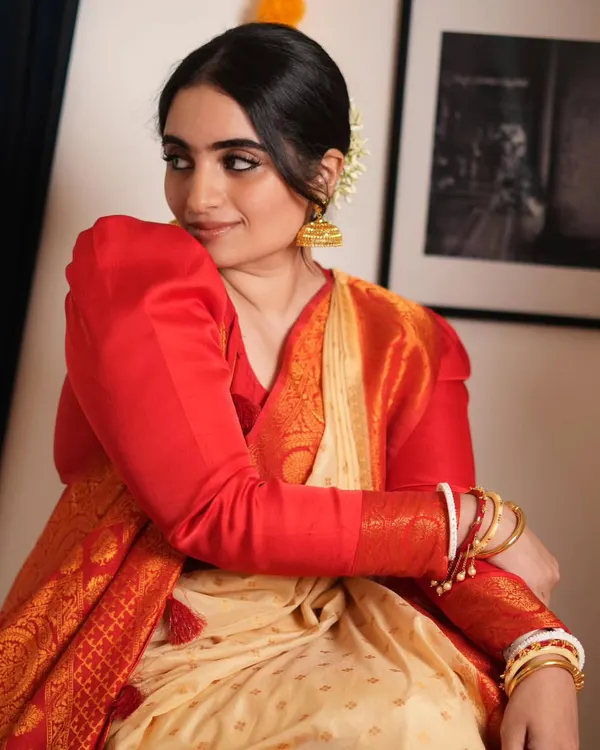 A beautiful moment captured, showcasing the elegance of a traditional Bengali saree. The puffed-sleeve blouse and classic red and cream saree are iconic, and I teach how to drape the fabric to achieve this soft, graceful fall.